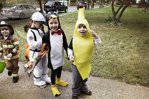 Fröhliche Kinder in Halloween-Kostümen  die während eines Streichs oder einer Behandlung auf dem Weg stehen