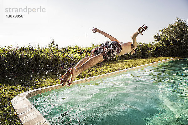 Mann springt in Schwimmbad gegen klaren Himmel
