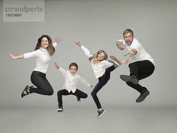 Porträt einer springenden Familie vor grauem Hintergrund