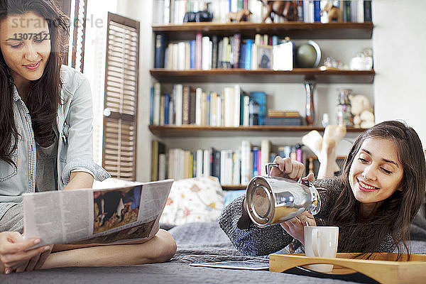 Frau liest Zeitung  während Schwester Kaffee in Tasse gießt