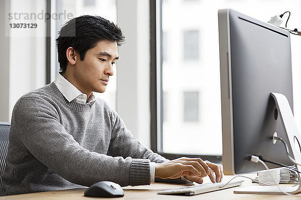 Mann arbeitet am Desktop-Computer im Büro