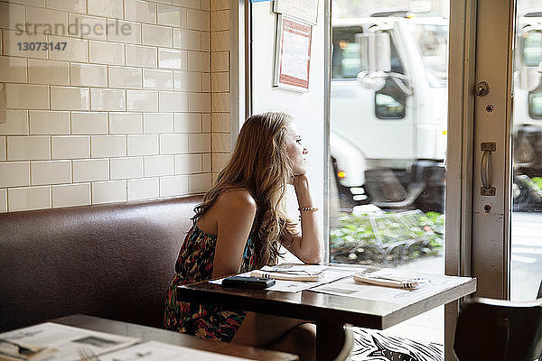 Seitenansicht einer nachdenklichen Frau  die beim Sitzen im Restaurant wegschaut