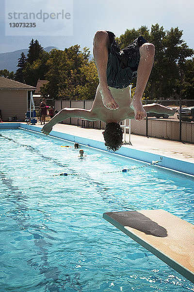 Rückansicht eines Teenagers  der in ein Schwimmbad springt