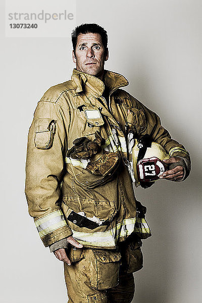 Porträt eines Feuerwehrmannes mit Helm vor weissem Hintergrund stehend