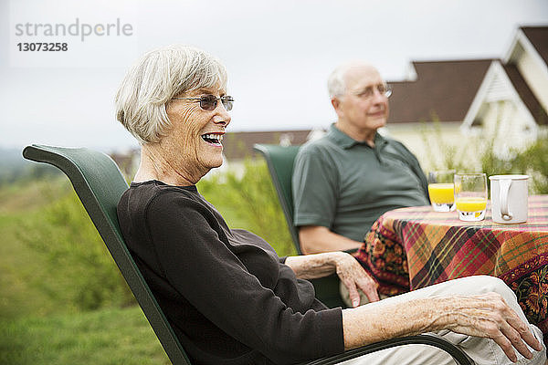 Ältere Frau schaut weg  während sie mit ihrem Mann am Tisch im Rasen sitzt