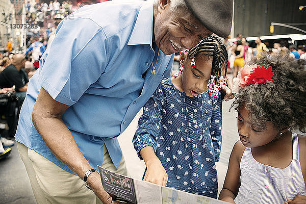 Glücklicher Großvater und Enkelkinder beim Blick auf die Karte in der Stadt