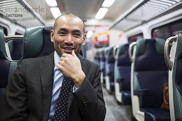 Glücklicher Geschäftsmann schaut weg  während er in der U-Bahn reist