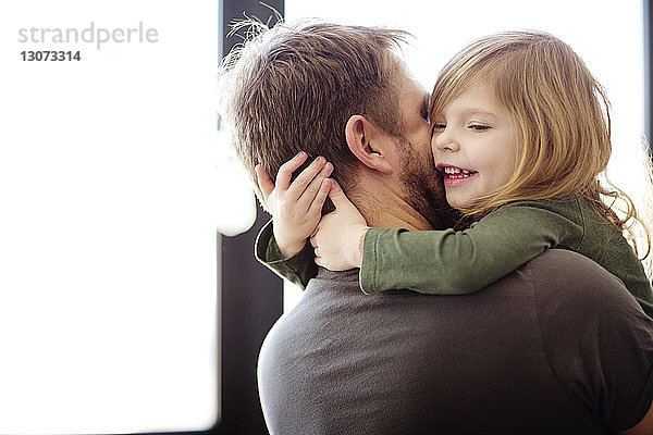 Glücklicher Vater umarmt Tochter zu Hause