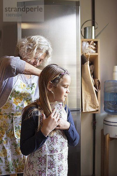 Frau bindet Enkelin die Schürze zu  während sie in der Küche steht