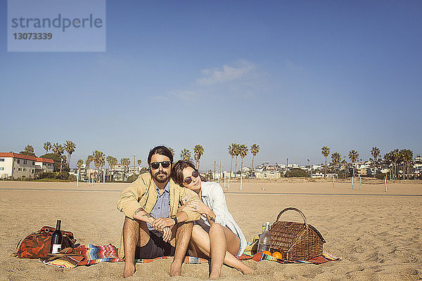 Paar entspannt am Strand vor blauem Himmel an einem sonnigen Tag