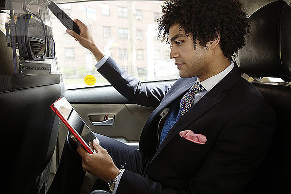 Mann benutzt Tablet-Computer  während er im Auto sitzt
