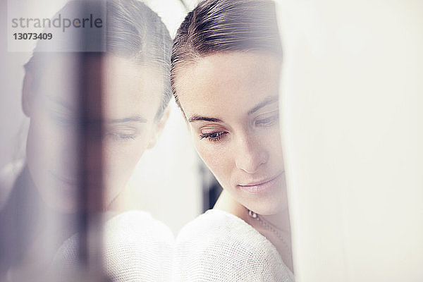 Nahaufnahme einer am Fenster lehnenden Frau