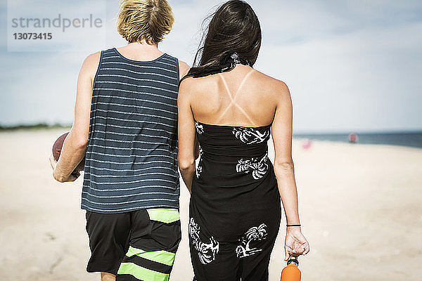 Rückansicht eines Paares  das am Strand auf Sand läuft