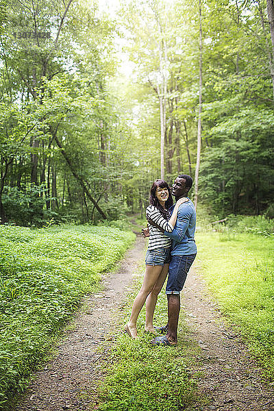 Glückliches Paar umarmt sich im Wald stehend