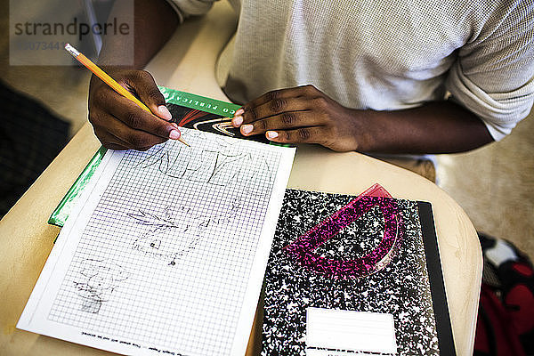 Hochwinkelansicht eines Teenagers  der im Klassenzimmer auf Millimeterpapier zeichnet
