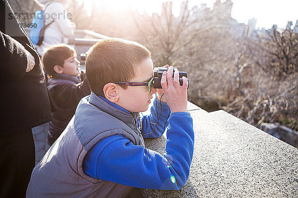 Jungen  die durch ein Fernglas schauen  während sie mit dem Vater am Beobachtungspunkt stehen