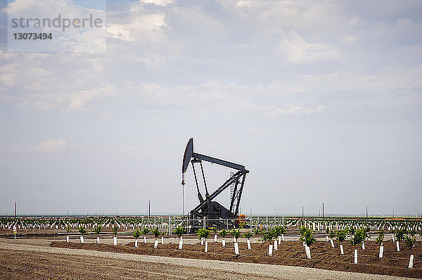 Ölpumpe auf landwirtschaftlichem Feld gegen den Himmel