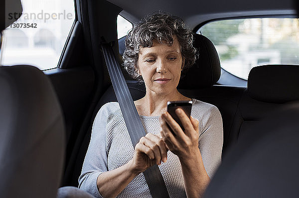 Ältere Frau telefoniert auf Reisen im Auto