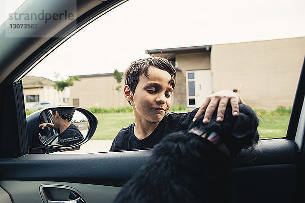 Junge streichelnder Hund im Auto sitzend