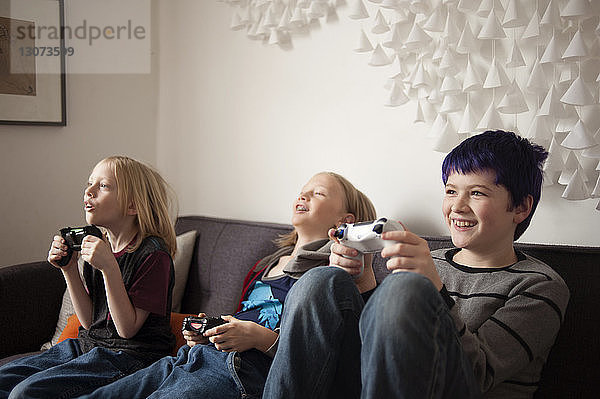 Jungen  die auf dem Sofa sitzen und Videospiele spielen