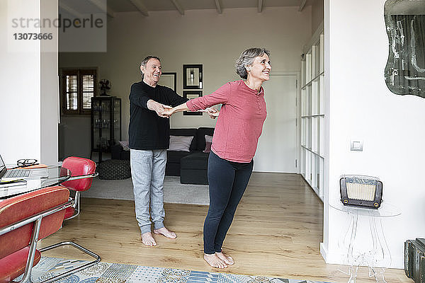 Älterer Mann assistiert Frau beim Yoga
