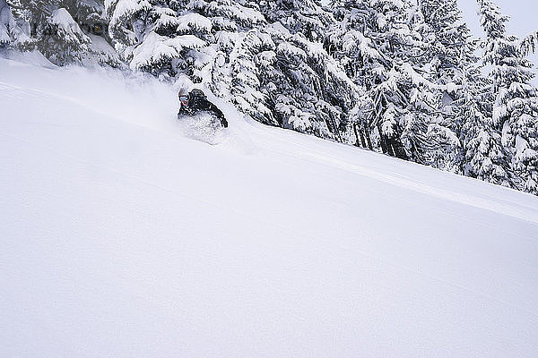 Mann fährt im Winter auf dem Berg Snowboard