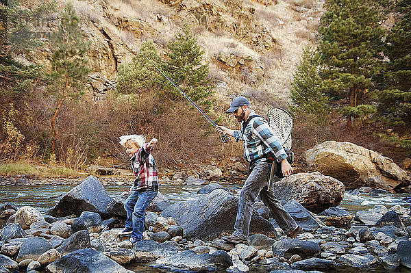 Vater und Sohn gehen auf Felsen inmitten eines Flusses am Berg
