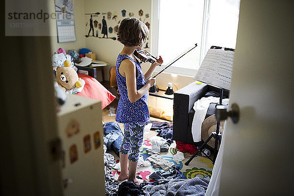 Rückansicht eines geigenspielenden Mädchens im Schlafzimmer