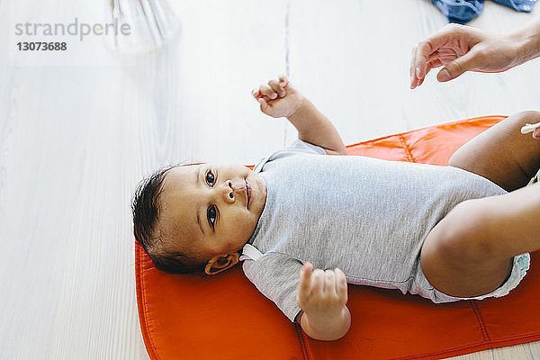 Gekrümmte Hand der Mutter  die nach dem zu Hause auf der Babydecke liegenden Sohn streckt