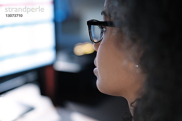 Nahaufnahme einer Geschäftsfrau mit Brille beim Blick auf den Computer im Büro