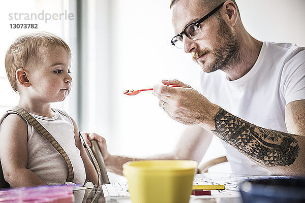 Wütender Vater füttert Tochter am Frühstückstisch