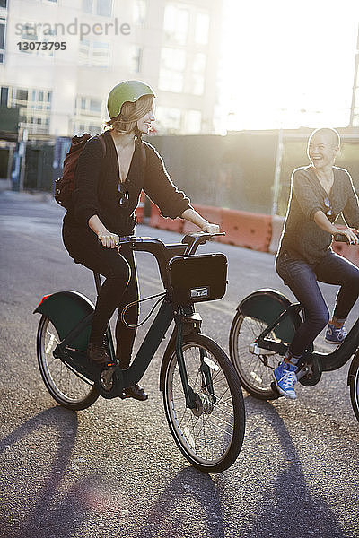 Glückliche Freunde fahren Fahrrad auf der Straße in der Stadt