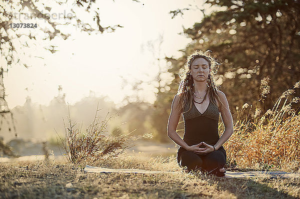 Junge Frau meditiert auf dem Feld