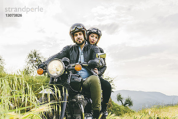 Porträt eines auf einem Motorrad sitzenden Paares gegen den Himmel