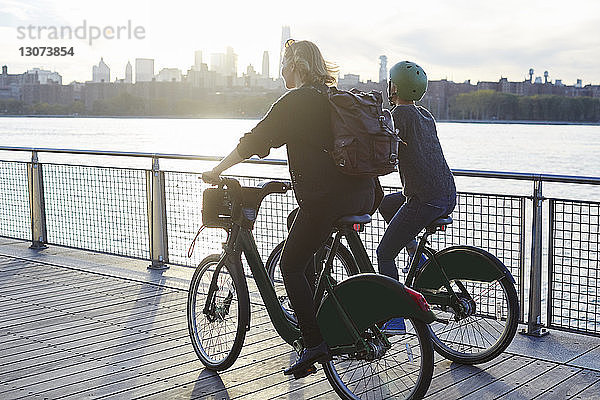 Freunde fahren Fahrrad auf der Promenade am Fluss