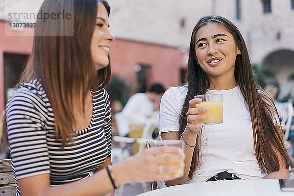 Freunde mit Getränken unterhalten sich am Tisch im Straßencafé