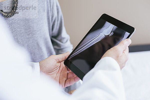 Nahaufnahme eines Arztes  der dem Patienten das Röntgenbild am Tablet-Computer erklärt