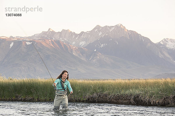 Junge Frau beim Fliegenfischen im Owens River gegen Berge