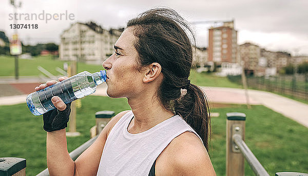 Frau trinkt Wasser beim Sport im Park