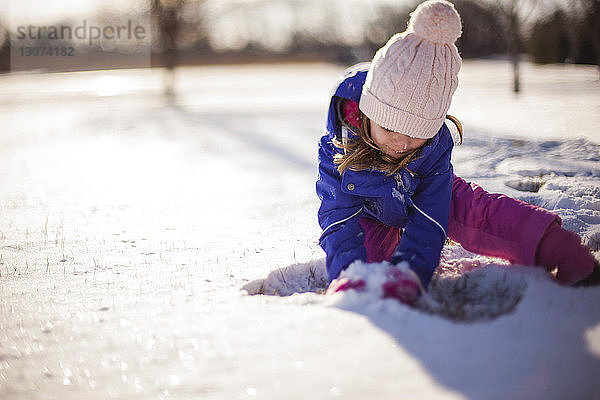 Mädchen spielt mit Schnee an einem sonnigen Tag