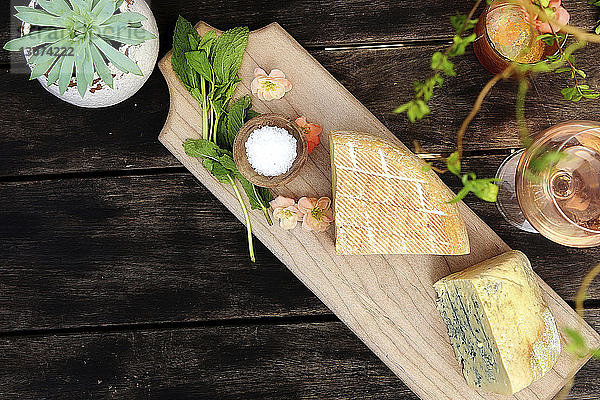 Hochwinkelansicht von Käse mit Wein und Pflanzen auf Holztisch