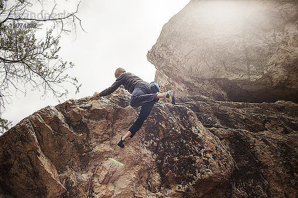 Tiefwinkelansicht eines Mannes  der an einem sonnigen Tag vom Felsen springt