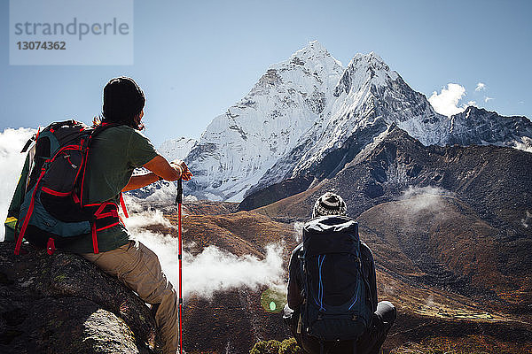 Freunde sitzen auf Berg gegen blauen Himmel im Sagarmatha-Nationalpark