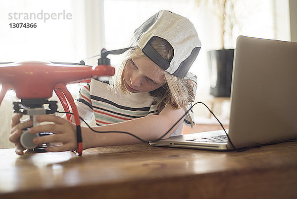 Junge arbeitet zu Hause mit seinem Laptop an der Drohne