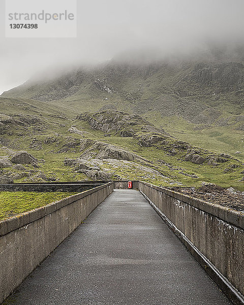Landschaftliche Ansicht einer leeren Straße inmitten eines Berges bei nebligem Wetter