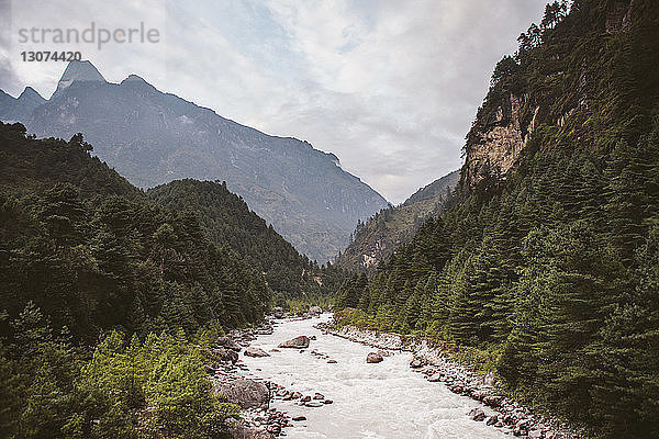 Landschaftliche Ansicht des Flusses  der inmitten der Berge vor bewölktem Himmel im Sagarmatha-Nationalpark fließt