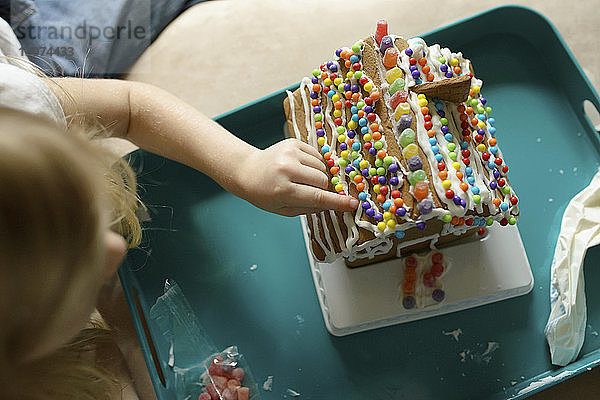 Hochwinkelansicht eines Mädchens  das zu Hause sein Spielzeughaus dekoriert