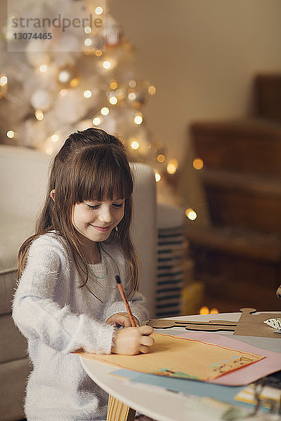 Lächelndes Mädchen zeichnet zu Hause auf Papier