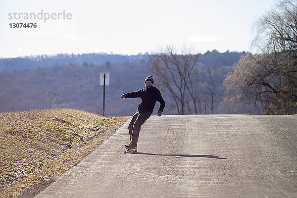Skateboardfahren in voller Länge auf der Landstraße während des Urlaubs