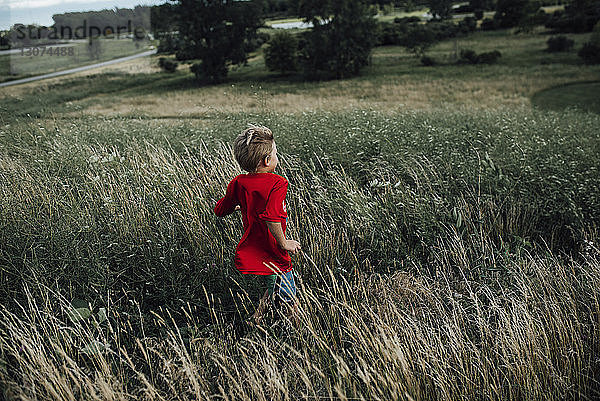 Rückansicht eines Jungen  der auf einem Grasfeld läuft